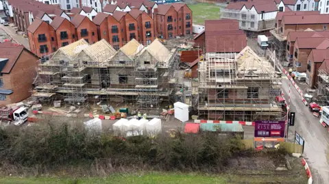 PA Construction work on part of the Chilmington Green housing development in Ashford, Kent. The picture shows half-built houses with scaffolding on, with completed three-storey buildings behind