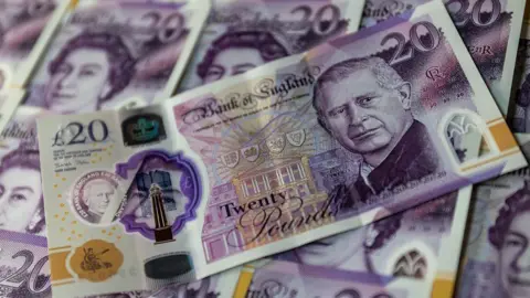 A pile of money. English £20 notes with the King and Queen on them.