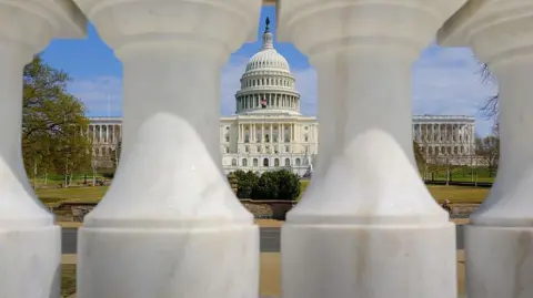 The US Capitol is seen between two marble pillars 