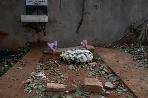 Joel Gunter/BBC The temporary grave where Saeed, Naya and Tea were buried. The cemetery was badly damaged by an Israeli air strike.