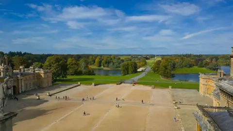 Carmel Jane The grounds and estate of Blenheim Palace from a bird's eye view. There are a few people walking along. It is a sunny day.