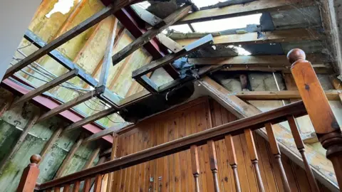 Andrew Turner/BBC The bare beams and roof area with daylight visible through the holes, burned through in the fire in 2021.