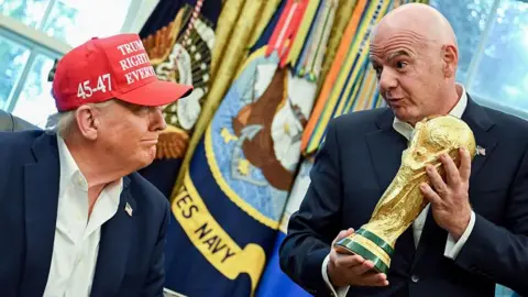 Donald Trump looking at Gianni Infantino holding the World Cup