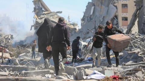 Palestinians walk through rubble in Khan Younis (file photo)