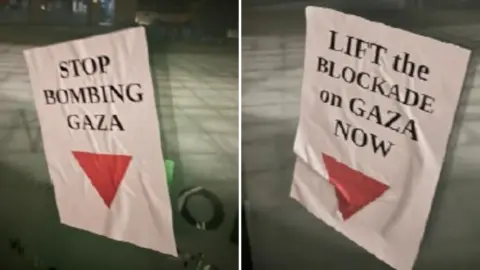 supplied Posters left at the scene attached to windows at the Forum building in Norwich, which say "Stop Bombing Gaze" and "Lift the Blockade on Gaza Now", with a red triangle symbol pointing downwards