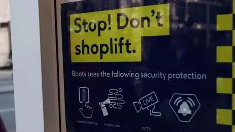 EPA A shop sign which says, Stop! Don't shoplift. Boots uses the following security protection.
