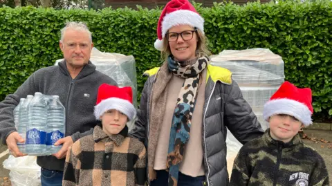The Anderson family from Bayleys Hill Sevenoaks collecting bottled water at the Solefields Road Car Park in Sevenoaks.