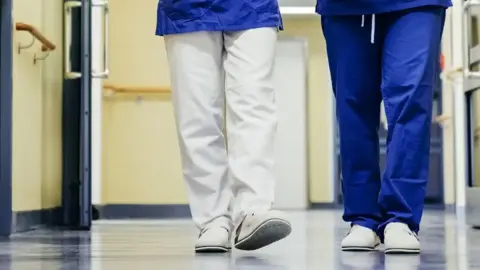 Two unidentified members of staff walk down a hospital corridor,
