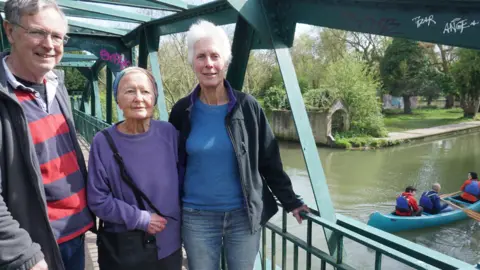 Tom Bragg Michael Goodhart, Jean Perraton and Anne Miller standing on a bridge over the River Cam