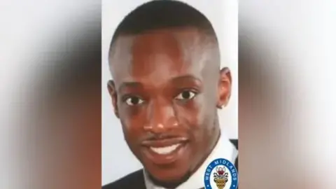 The head and shoulders image shows Trey smiling at the camera wearing a white shirt and black top. He has closely cropped hair and a small beard.