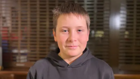 Artem is wearing a grey hoodie