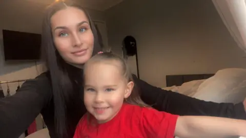 Paige Summers Mother wearing a black top and daughter wearing a red top looking at the camera