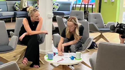 Lois using a colouring book as Inspire staff sit next to her