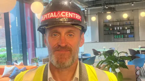 Photograph of Paul Richards, the deputy chief executive of Stockport Council. He is pictured in a hard hat and a hi-vis jacket.