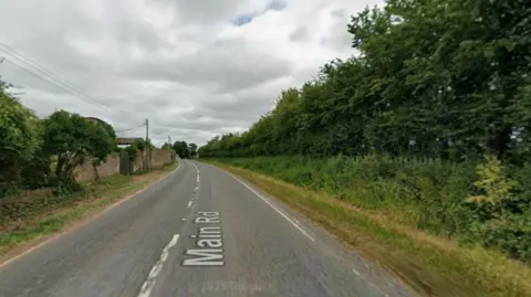 Google A view of the A361 in West Lyng with hedges on either side and a grey sky above.