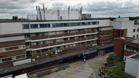 Steve Hubbard/BBC Aerial image showing the exterior of Kettering General Hospital, a five-storey building with a mix of dark red and white external walls