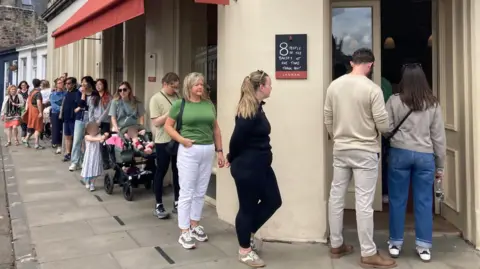 A large queue snakes down the street outside the bakery.