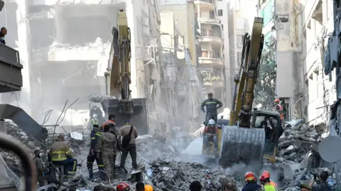 Getty Images Workers and heavy machinery work through the rubble at the site of a massive Israeli airstrike in central London.