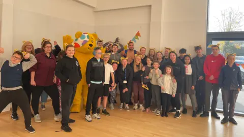 A picture of a group of pupils at The Fusion Academy in Barwell, Leicestershire with Pudsey the bear and BBC Gladiator star Steel.