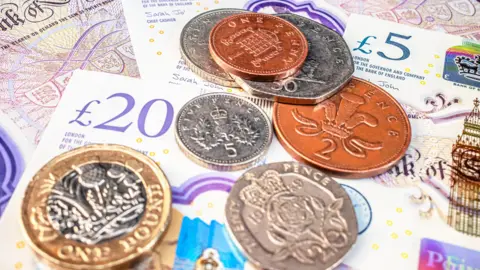A pile of UK banknotes and coins.