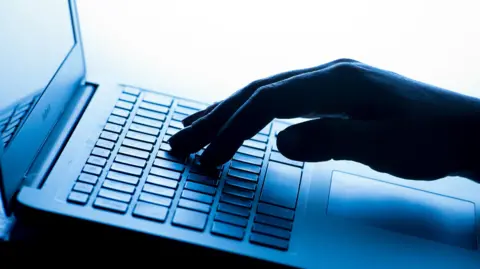 A hand typing on a laptop keyboard. 