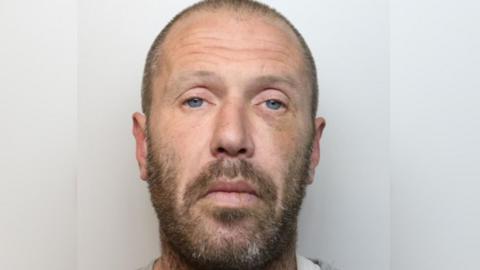 A police custody image of Dean Cochrane, who is wearing a light grey sweatshirt. 