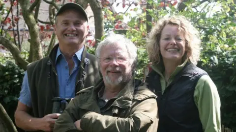 Springwatch presenters Simon King, Bill Oddie and Kate Humble. They are photographed outside in a garden