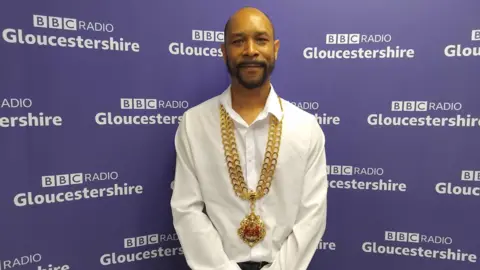 Mayor of Gloucester Adrian Graham wearing his ceremonial chain stares into camera in photo taken at BBC Radio Gloucestershire studios 