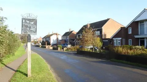 A road in Martham, Norfolk, showing a sign for Martham and a number of houses 