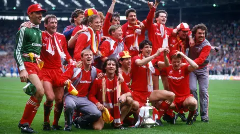 Getty Images Liverpool's players pose for a photograph around the FA Cup on the pitch at Wembley stadium