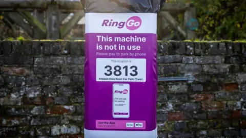 A parking meter with a large sign on its face which says: "This machine is not in use" and shows instructions on how to pay using the Ringo app.