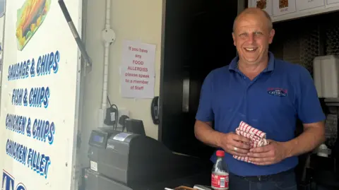 El propietario de una furgoneta Chipvan se encuentra en su caja atendiendo a los clientes