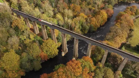 Christopher Furlong/Getty Images An aerial view of a canal boat crossing the Pontcysyllte Aqueduct as autumnal colours begin to appear on the trees and foliage on the banks of the River Dee near Llangollen, Denbighshire.
