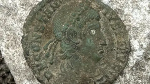 Worthing Museum A Roman coin, with the face of a late emperor stamped on it.