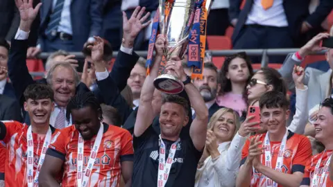 Rob Edwards lifts the play-off winners' trophy 
