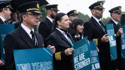A number of striking Aer Lingus pilots standing outside Dublin airport holding placards