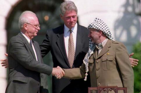 US President Bill Clinton (centre) stands between PLO leader Yasser Arafat (right) Israeli Prime Minister Yitzhak Rabin, as the two shake hands.