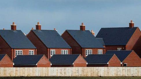 A row of new-build red brick houses set against a blue sky