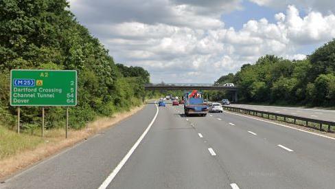A google maps image of the A2 carriageway with vehicles driving on both sides of the road, a green sign to the left and a road bridge up ahead