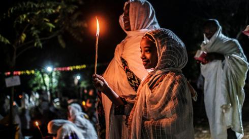 A woman and girl holding at candle at the Fasilides Bath during Timket in Gondar, Ethiopia - Wednesday 19 January 2022
