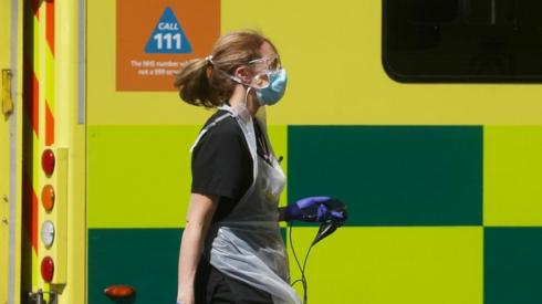 A medical worker walking in front of an ambulance