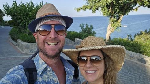 Selfie of Richard Orna and wife Maja in hats by the sea.