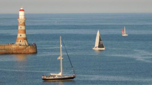 Boats sailing by Roker Pier Lighthouse in Sunderland