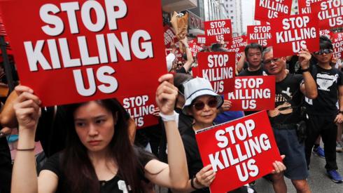 Protesters hold placards as they attend a demonstration demanding Hong Kong"s leaders to step down and withdraw the extradition bill, in Hong Kong, China