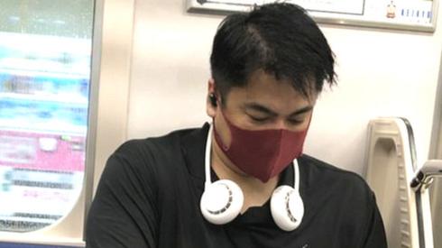 A neck fan being worn on the Tokyo Metro