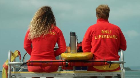 Male and female lifeguards look out to sea
