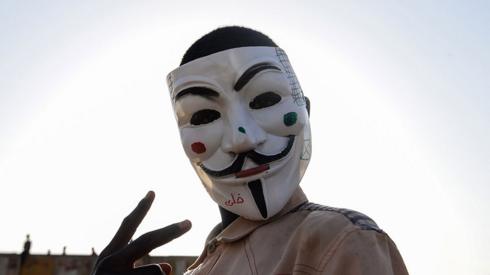 A Sudanese protester wears a Guy Fawkes mask outside the army headquarters in Khartoum on May 6, 2019. - Defiant Sudanese protesters broke their fast on the first day of Ramadan today with chicken soup and beans, vowing to press on with their campaign for a civilian rule. As the call for the evening Maghreb prayer echoed, crowds of protesters gathered at the sit-in area in central Khartoum for iftar after a day of sweltering heat, an AFP correspondent reported.