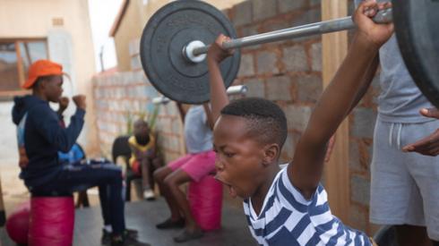 A young boy lifts heavy weights at a training session in Soweto, South Africa - Thursday 27 January 2022