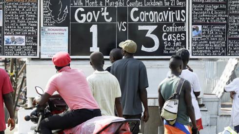 People reading a blackboard news board in Monrovia, Liberia - Monday 30 March 2020