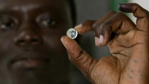 A voter in Gambia holding up a marble used to vote - archive shot